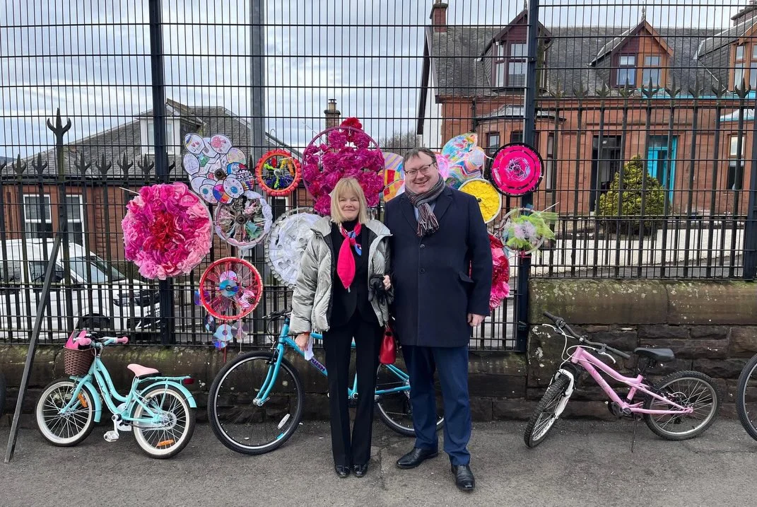 Two people standing in front of a display of decorated bicycle wheels