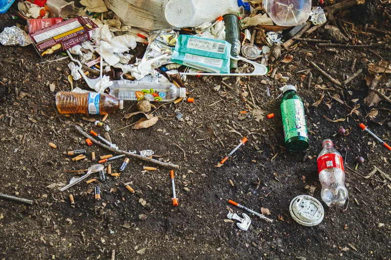 syringes and old bottles laying on the ground